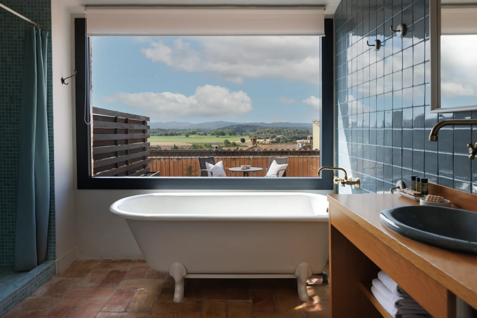 Baño de suite con bañera exenta y vistas panorámicas al paisaje desde un hotel boutique.